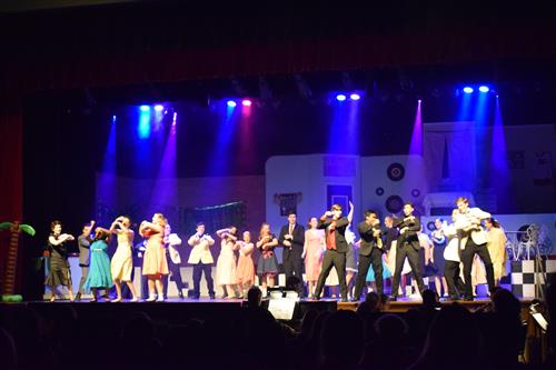 students on stage in a production of grease 